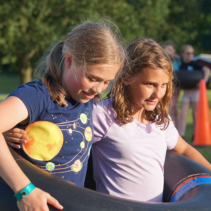 Two campers stand together in an inner tube ready to race